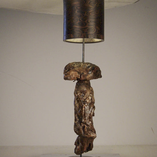 Driftwood Light Sculpture LO05 – Treibholz Lampe mit Echtholz Furnier & Beton-Sockel, beleuchtet im dunklen Raum mit Lichtreflexionen.